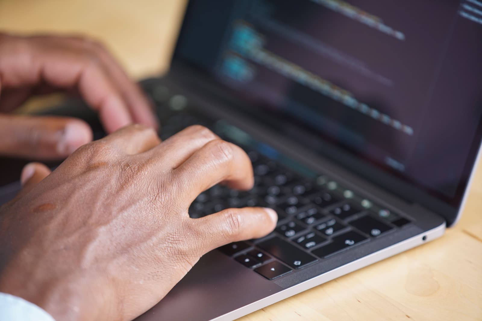 Hands typing on a laptop while reviewing software