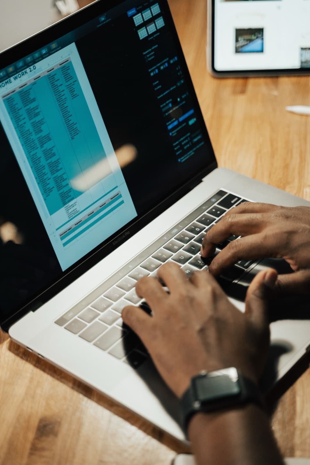 Hands typing on a laptop at a wooden desk while reviewing software